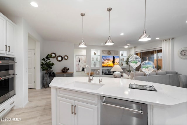 kitchen featuring open floor plan, light countertops, appliances with stainless steel finishes, white cabinets, and a sink