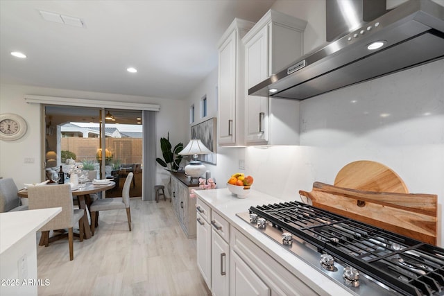 kitchen with visible vents, stainless steel gas cooktop, light countertops, white cabinetry, and exhaust hood