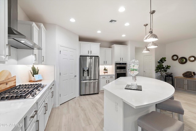 kitchen featuring visible vents, appliances with stainless steel finishes, white cabinetry, and wall chimney range hood