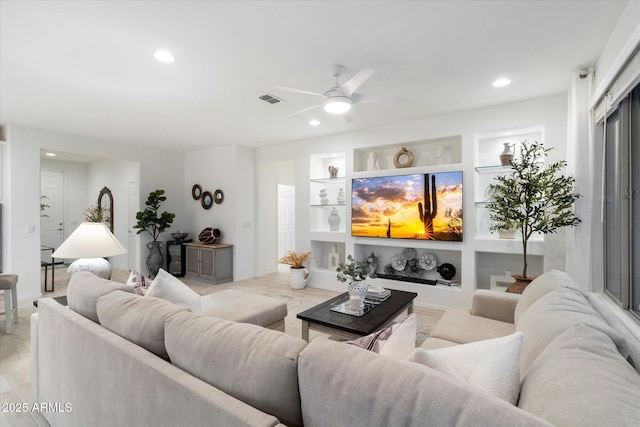 living room featuring built in features, light wood-type flooring, visible vents, and recessed lighting