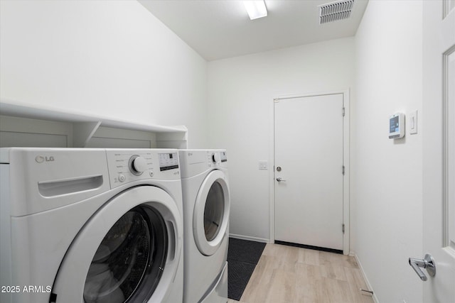 laundry room featuring visible vents, light wood-style flooring, laundry area, and washer and clothes dryer