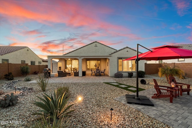 rear view of property featuring a fenced backyard, an outdoor living space, a patio, and stucco siding