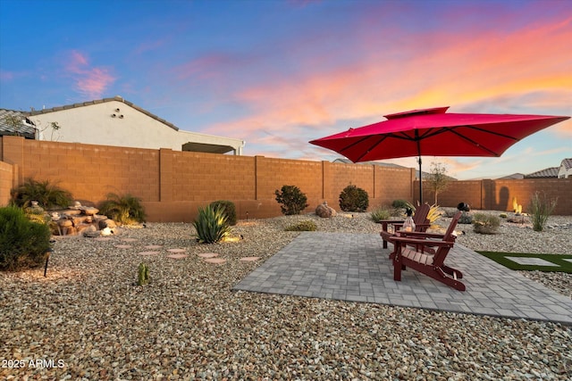 patio terrace at dusk featuring a fenced backyard