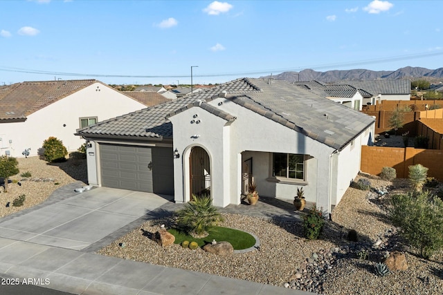 view of front facade featuring stucco siding, a tile roof, fence, concrete driveway, and an attached garage