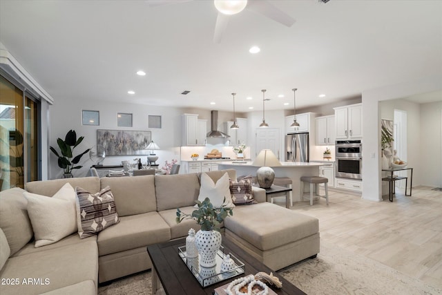 living area with recessed lighting, ceiling fan, and light wood finished floors