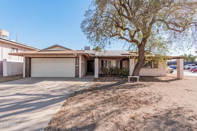 ranch-style home featuring a garage and solar panels