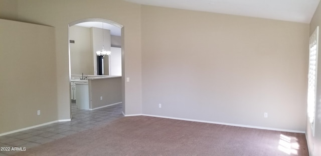 spare room with an inviting chandelier, sink, and light colored carpet