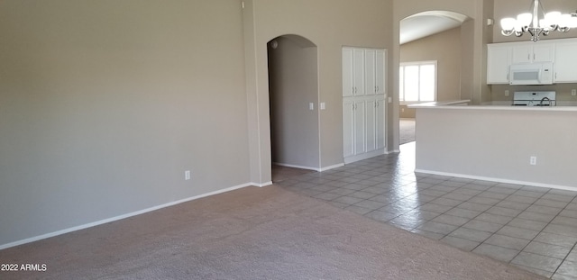 tiled empty room featuring an inviting chandelier and high vaulted ceiling