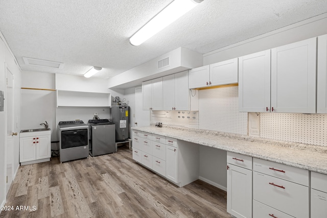 kitchen featuring white cabinets, washer and clothes dryer, water heater, light hardwood / wood-style floors, and decorative backsplash