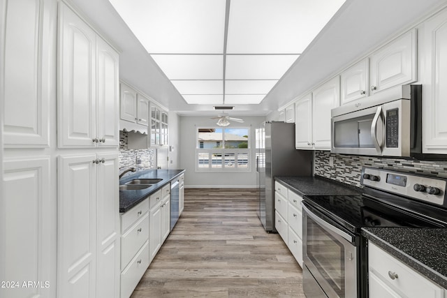 kitchen featuring sink, white cabinetry, appliances with stainless steel finishes, light hardwood / wood-style floors, and decorative backsplash