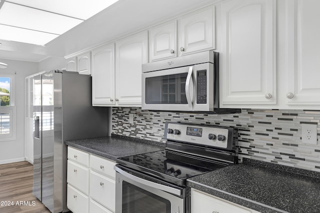 kitchen with white cabinets, hardwood / wood-style flooring, stainless steel appliances, and tasteful backsplash