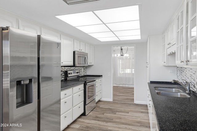 kitchen featuring white cabinets, sink, backsplash, stainless steel appliances, and light hardwood / wood-style floors