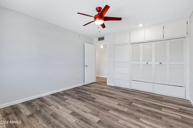 unfurnished bedroom featuring ceiling fan, wood-type flooring, a closet, and a textured ceiling