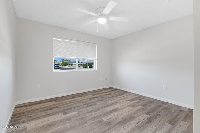 empty room with a textured ceiling, ceiling fan, and light hardwood / wood-style flooring