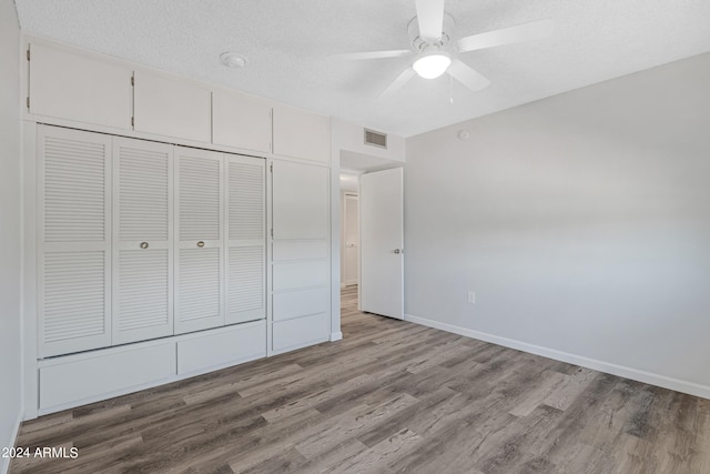 unfurnished bedroom with ceiling fan, a textured ceiling, light wood-type flooring, and a closet