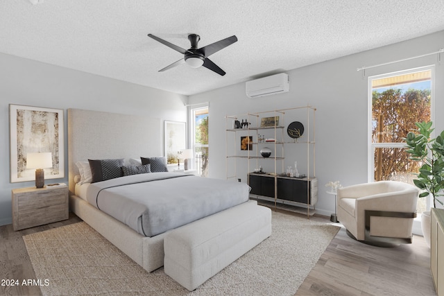 bedroom featuring multiple windows, hardwood / wood-style floors, a wall unit AC, and ceiling fan