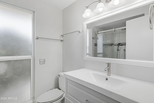 bathroom with a shower with shower door, vanity, and toilet