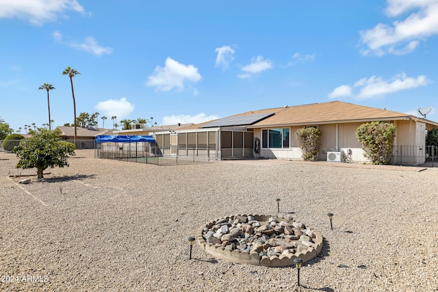 back of house with ac unit, solar panels, a patio area, and an outdoor fire pit