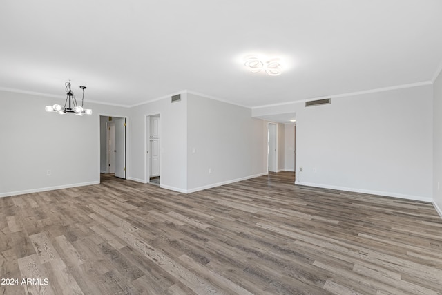 spare room featuring a notable chandelier, crown molding, and light hardwood / wood-style floors