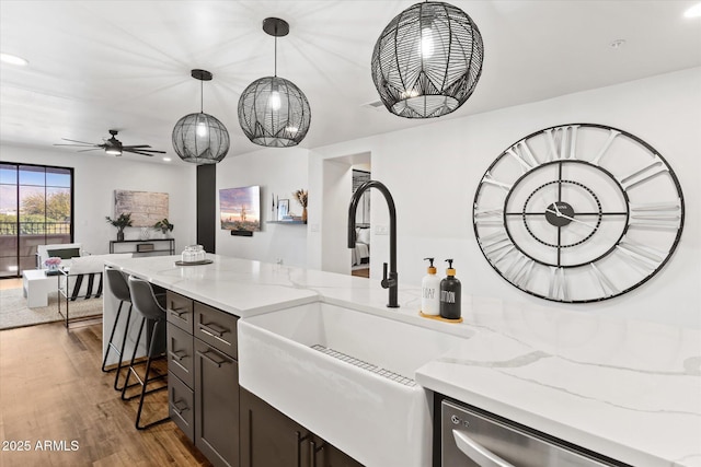 kitchen with hardwood / wood-style floors, sink, light stone countertops, and hanging light fixtures