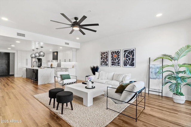 living room with light hardwood / wood-style flooring and ceiling fan