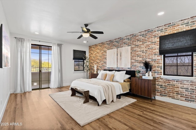 bedroom with access to outside, ceiling fan, brick wall, and light wood-type flooring