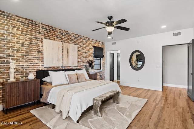 bedroom with ceiling fan, brick wall, and hardwood / wood-style flooring