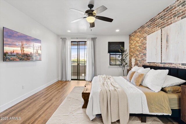 bedroom featuring access to outside, light hardwood / wood-style flooring, ceiling fan, and brick wall