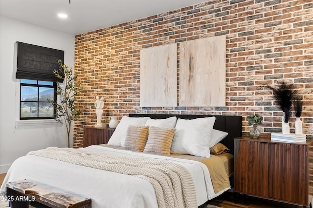 bedroom with dark hardwood / wood-style flooring and brick wall