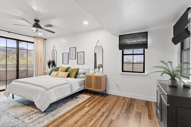 bedroom featuring access to outside, multiple windows, ceiling fan, and wood-type flooring