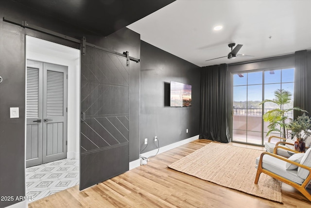 interior space with a barn door, ceiling fan, and light wood-type flooring