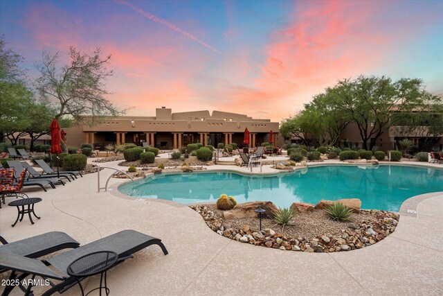 pool at dusk featuring a patio area