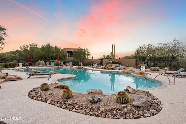 pool at dusk featuring a patio