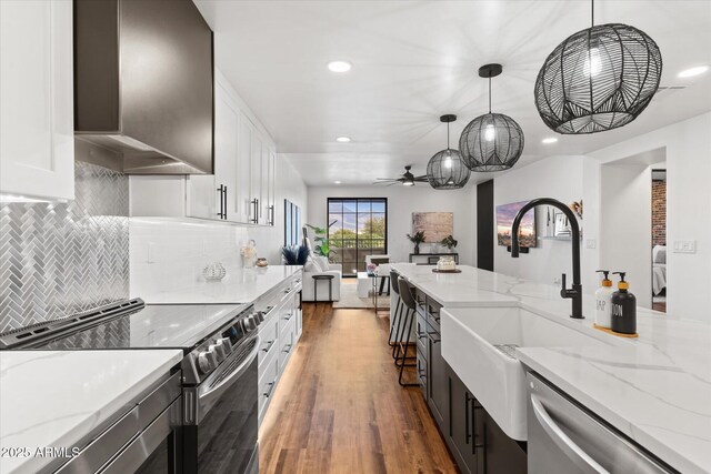 kitchen with light stone countertops, pendant lighting, stainless steel appliances, and white cabinetry