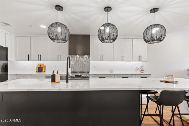 kitchen with light stone counters, a kitchen island, and pendant lighting