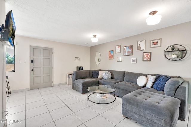 living area featuring a textured ceiling, light tile patterned flooring, and baseboards