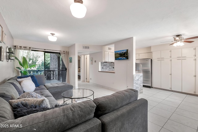 living area featuring light tile patterned floors, a ceiling fan, visible vents, and a textured ceiling