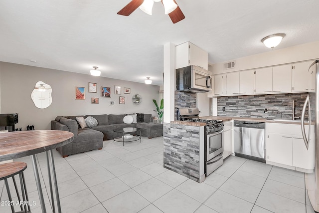 kitchen with light tile patterned floors, visible vents, decorative backsplash, appliances with stainless steel finishes, and open floor plan