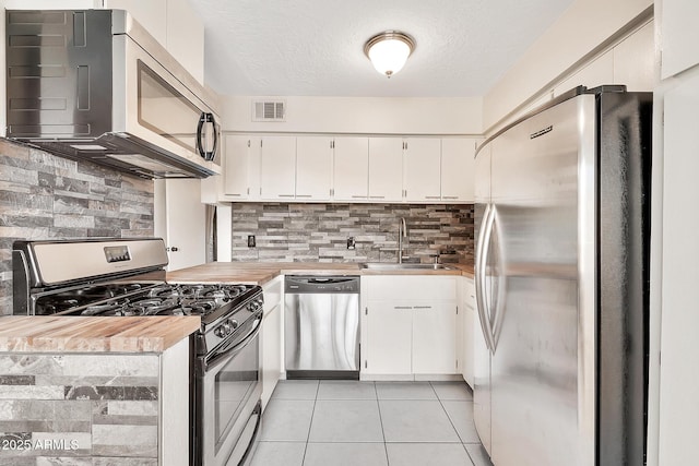 kitchen with light tile patterned floors, visible vents, stainless steel appliances, white cabinetry, and a sink