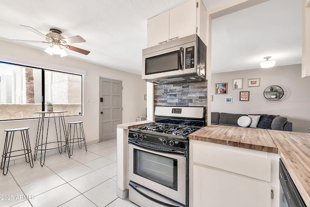 kitchen with light tile patterned floors, stainless steel appliances, butcher block counters, white cabinetry, and backsplash