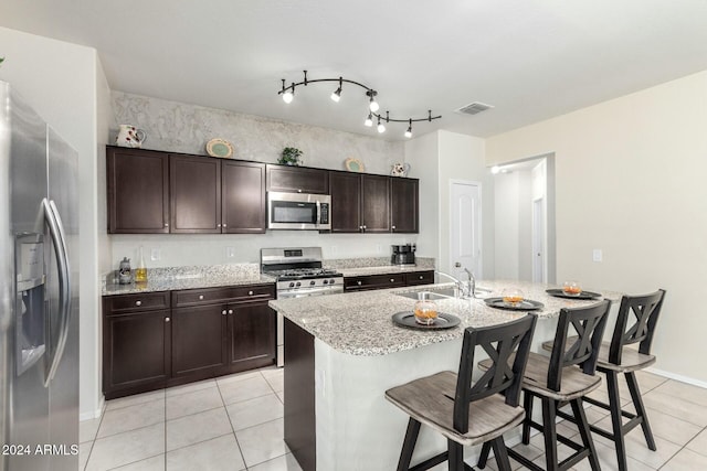 kitchen featuring a breakfast bar, sink, an island with sink, dark brown cabinetry, and stainless steel appliances