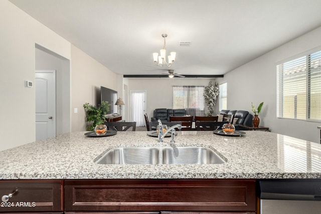 kitchen featuring ceiling fan with notable chandelier, dark brown cabinetry, hanging light fixtures, and sink