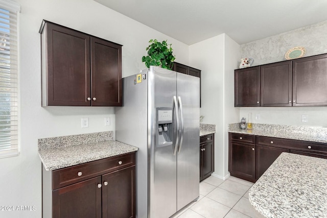 kitchen featuring light stone counters, dark brown cabinets, light tile patterned floors, and stainless steel refrigerator with ice dispenser