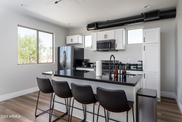 kitchen featuring appliances with stainless steel finishes, white cabinets, a kitchen island with sink, and dark hardwood / wood-style floors