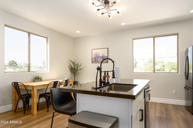 kitchen with hardwood / wood-style flooring, stainless steel refrigerator, sink, and a breakfast bar area