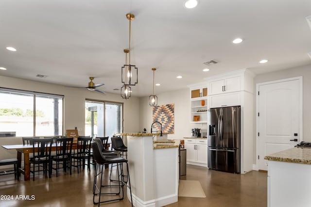 kitchen with white cabinetry, light stone countertops, decorative light fixtures, and stainless steel refrigerator with ice dispenser