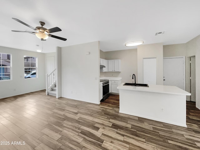 kitchen featuring visible vents, stainless steel electric stove, a sink, and wood finished floors