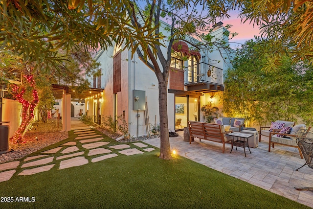 8001 N 3rd Pl, Phoenix, AZ 85020 - back of house at dusk with a balcony, an outdoor living space, a patio area, stucco siding, and a lawn