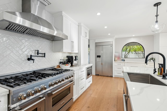 8001 N 3rd Pl, Phoenix, AZ 85020 - kitchen with wall chimney exhaust hood, stainless steel appliances, light wood-style floors, white cabinets, and recessed lighting