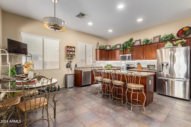 kitchen featuring a center island, a kitchen breakfast bar, backsplash, light stone countertops, and appliances with stainless steel finishes